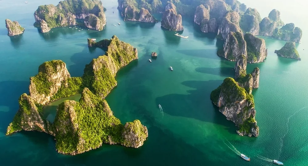 Vue panoramique aérienne des îlots karstiques verdoyants dispersés sur les eaux émeraude de la baie d'Ha Long.