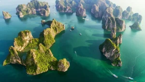 Vue panoramique aérienne des îlots karstiques verdoyants dispersés sur les eaux émeraude de la baie d'Ha Long.