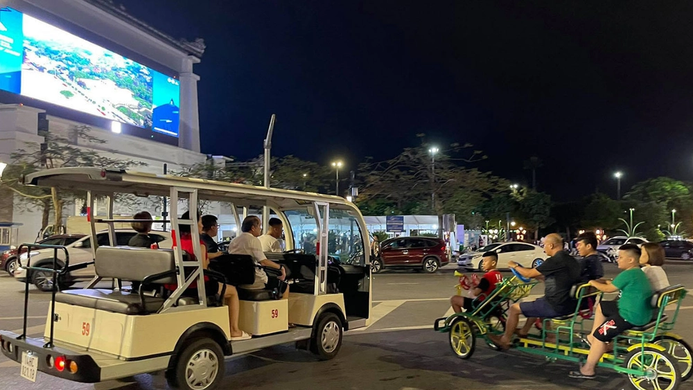 Voiturette électrique touristique transportant des visiteurs en ville pendant la nuit.