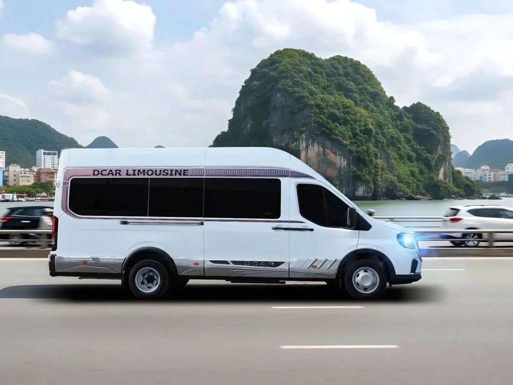 Minibus limousine blanc roulant le long de la côte avec les montagnes karstiques en arrière-plan.