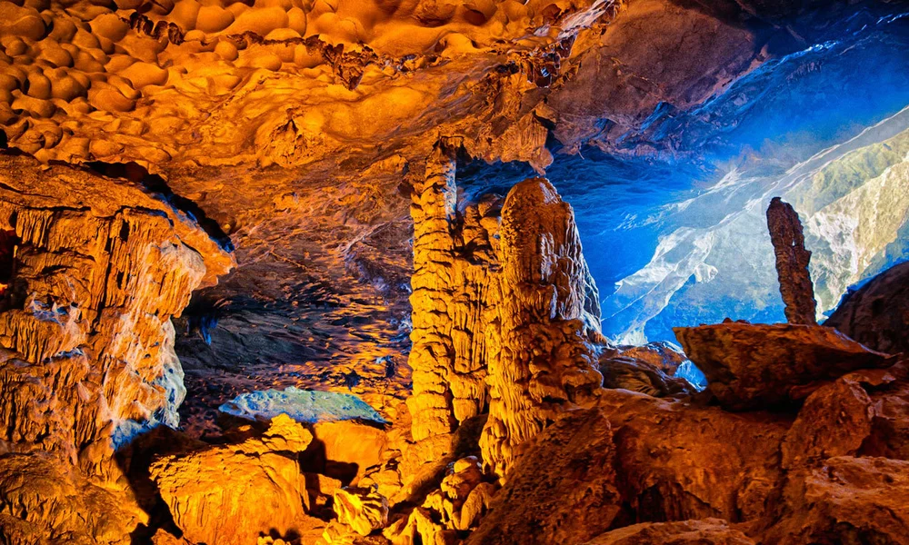 Intérieur majestueux de la grotte de la Surprise illuminé par des lumières colorées mettant en valeur les stalagmites.
