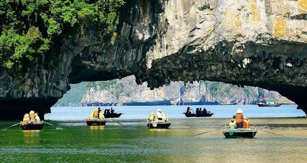 Barques passant sous la voute de la grotte Luồn.
